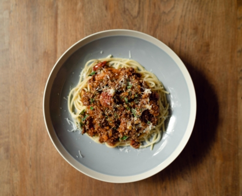 Pasta Bolognese in a bowl on a wooden table.